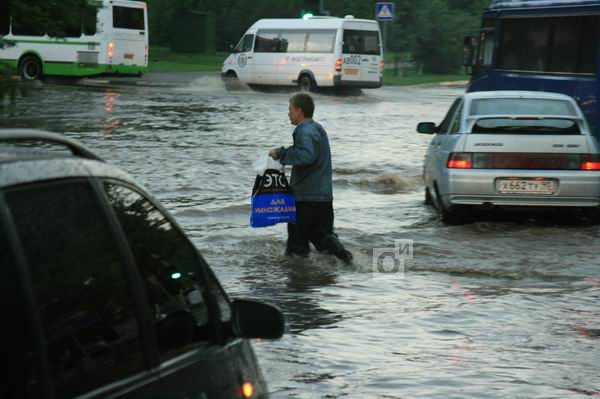 Пешеход переходит затопленную улицу Одинцово