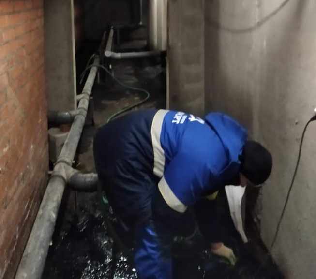 Сотрудник управляющей компании в подвале дома, Управляющая компания осушила затопленный подвал по требованию Госжилинспекции
